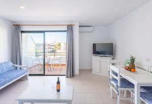 a living room with a couch and a table and a tv at Apartamentos Es Dolç in Colònia de Sant Jordi