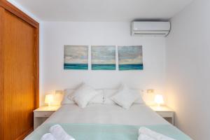 a bedroom with a white bed with two lamps at Apartamentos Es Dolç in Colònia de Sant Jordi