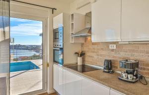 a kitchen with white cabinets and a view of a pool at Beautiful Home In Sevid Na Moru in Sevid