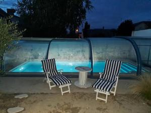 2 sillas y una mesa junto a la piscina en Chambre bleue avec accès plage en Bourges