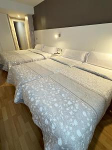 una fila de tres camas en una habitación en Hotel El Acebo en Jaca