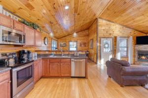 a kitchen with wooden cabinets and a couch in a cabin at Bear Cove by AvantStay Hot Tub Pool Table in Pigeon Forge