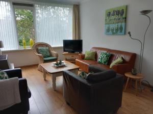 a living room with couches and a tv at Appartement AanZee in Hoek van Holland