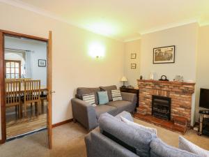 een woonkamer met een bank en een open haard bij 5 Melinda Cottages in West Runton