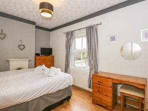 a bedroom with a bed and a fireplace and a window at 5 Melinda Cottages in West Runton