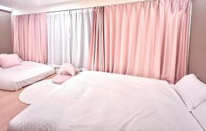 una camera con due letti e una finestra con tende rosa di 近秋叶原东京中心奢华套房KFob 车站2分 4站可用 配奢华戴森 最大5人 a Tokyo