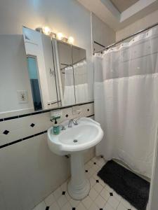 Baño blanco con lavabo y espejo en Comfy Guest House by Columbus Circle en Nueva York