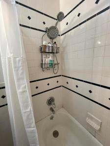 uma casa de banho com uma banheira e um chuveiro com azulejos pretos e brancos. em Comfy Guest House by Columbus Circle em Nova Iorque