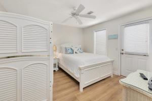 Un dormitorio con una cama blanca y un ventilador de techo. en Sea Haven 1532, en East End