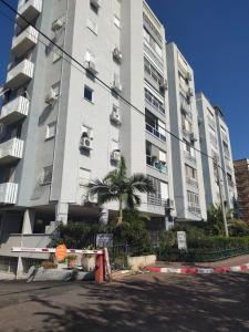 a tall building with a palm tree in front of it at Cozy and stylish 1-bedroom apartment in Netanya