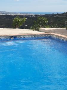 a large blue swimming pool with the ocean in the background at Casa Montaña Vélez-Málaga B&B in Vélez-Málaga