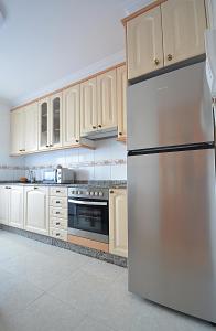 una nevera de acero inoxidable en una cocina con armarios de madera en Apartamento As Carolinas, en Vilagarcía de Arousa