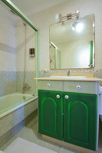 La salle de bains est pourvue d'un lavabo vert et d'un miroir. dans l'établissement Apartamento As Carolinas, à Vilagarcía de Arousa