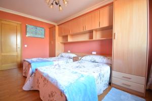 2 camas en una habitación con paredes de color naranja y armarios de madera en Apartamento As Carolinas en Vilagarcía de Arousa