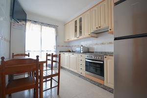 - une cuisine avec des placards blancs, une table et une cuisinière dans l'établissement Apartamento As Carolinas, à Vilagarcía de Arousa