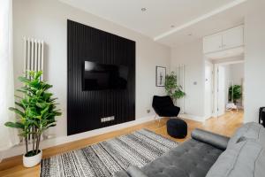 uma sala de estar com um sofá e uma televisão na parede em Contemporary & Chic 1 Bedroom Apartment in Honor Oak em Londres