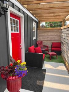 un patio con una puerta roja, sillas y flores en Red door retreat guesthouse en Thorold