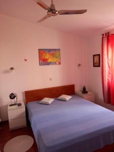 Schlafzimmer mit einem blauen Bett und einem Deckenventilator in der Unterkunft APARTMAN SILVA in Biograd na Moru