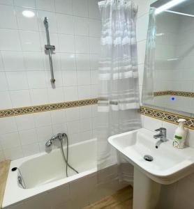 een witte badkamer met een wastafel en een bad bij Apartamentos Melgarden - Campo del Marqués in Santoña