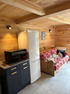 a kitchen with a refrigerator and a couch in a room at L'OURSIERE à Saint MAMET in Saint-Mamet