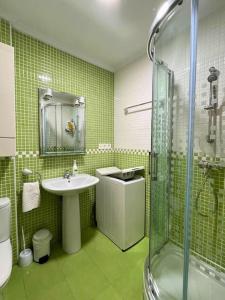 een groene badkamer met een wastafel en een douche bij Apartamentos Melgarden - Campo del Marqués in Santoña