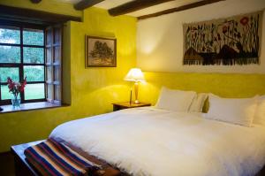 a bedroom with a white bed and a window at Hacienda San Agustin de Callo in Lasso