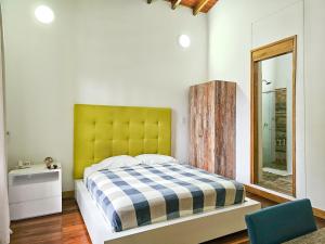 1 dormitorio con 1 cama con cabecero amarillo y espejo en La Mercedes Boutique Hostal By MH en Cali