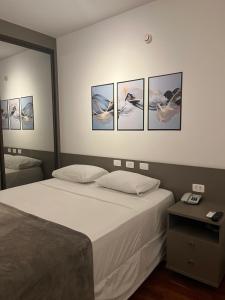 een slaapkamer met een bed met vier foto's aan de muur bij Flat Premium -Acesso a pé ao shopping Center vale - Edifício Summit (Ar condicionado) in São José dos Campos
