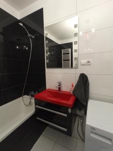 a bathroom with a red sink and a bath tub at Apartament Warmiński - Old Town in Biskupiec