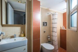 a bathroom with a sink and a toilet and a mirror at City Cave Apartment in Heraklio
