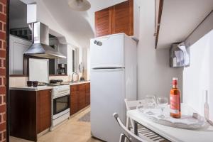City Cave Apartment في مدينة هيراكيلون: مطبخ مع ثلاجة بيضاء وطاولة مع زجاجة من النبيذ
