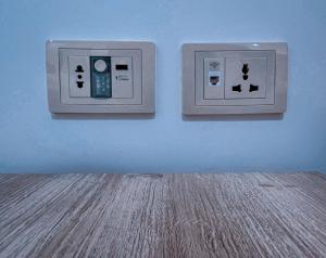 two light switches on a blue wall with a wooden floor at Petra Caravan Guest House in Wadi Musa