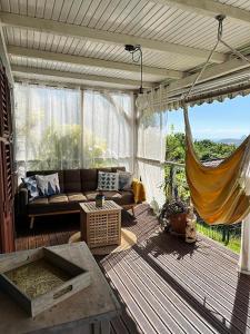 a porch with a couch and a hammock on a deck at Bungalow vue mer avec jardin in Sainte-Luce