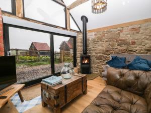 sala de estar con sofá y chimenea en The Old Cow House en Bridgnorth