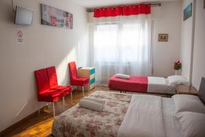 a bedroom with two beds and red chairs and a window at Holiday Guesthouse in Marghera