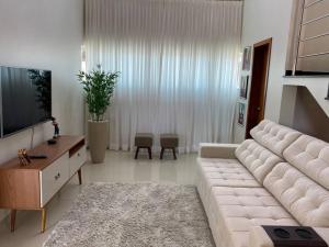 un salon avec un grand canapé blanc et une télévision dans l'établissement Casa Rondônia Rural show!, à Ji-Paraná