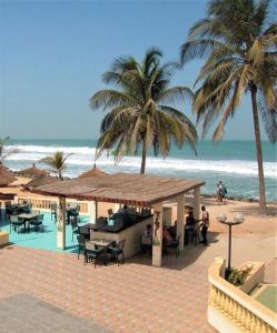 un restaurante en la playa con palmeras y el océano en Ya Aluga Apartment - Serekunda, en Serekunda