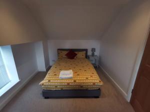 um quarto com uma cama com um edredão amarelo e branco em No.12 - The Meadow em Banbury