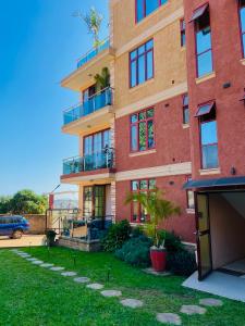 a tall brick building with a lawn in front of it at Keitylin Heights Apartments in Makindye in Kampala