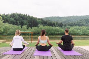 un gruppo di tre persone seduti in una posa yoga di TAOR Karpaty Resort & Spa a Skhidnytsia