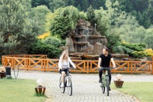 Un uomo e una donna in bicicletta in un parco di TAOR Karpaty Resort & Spa a Skhidnytsia