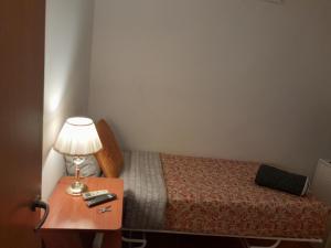 Habitación SF في مدريد: غرفة نوم صغيرة بها سرير وطاولة بها مصباح