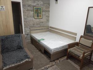 a bed and a chair in a room at Mini Garsonjera in Podgorica