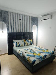 a bedroom with a large bed with a blue headboard at Résidences Hozy in Abidjan