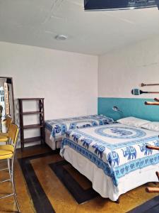 Habitación con 2 camas y una silla. en Apartamento Centro Histórico - Vila- Ilhabela, en Ilhabela