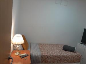 Habitación SF في مدريد: غرفة نوم بسرير ومصباح على طاولة