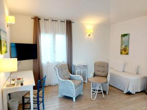 a room with a bed and two chairs and a desk at Hotel La Villa Del Mare in Cagliari