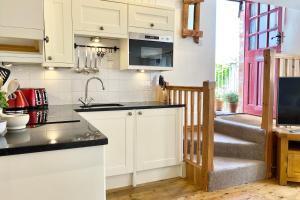 a kitchen with white cabinets and a staircase at Althea House with parking in Padstow