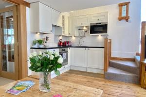 a kitchen with white cabinets and a vase of flowers on a table at Althea House with parking in Padstow