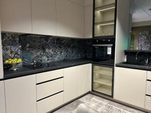 a kitchen with white cabinets and black counter tops at GT apartments in Chisinau in Chişinău